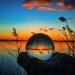 Creative crystal lens ball photography of a lake with greenery around at dawn